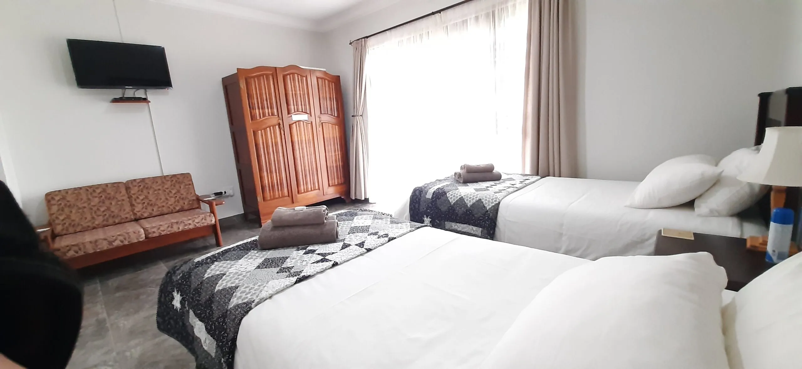 Bedroom with two single beds sofa wardrobe and TV on the wall