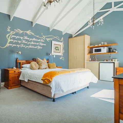 Cozy bedroom with a double bed wooden furniture and a small kitchenette