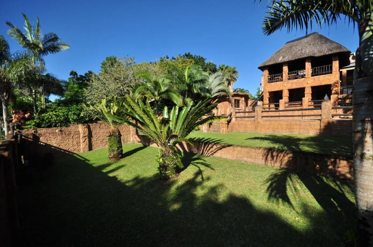 Tropical garden with large plants and a traditional brick building in the background