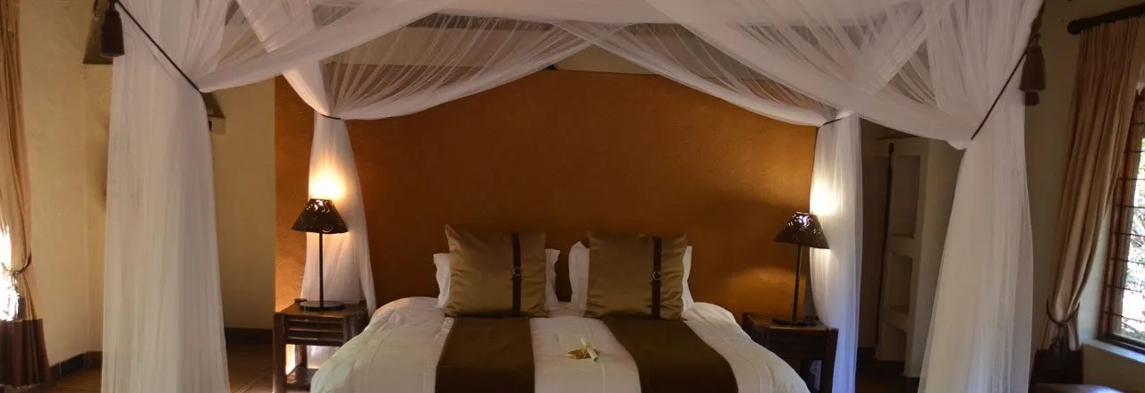 A bed with a canopy pillows and bedside lamps in a cozy bedroom