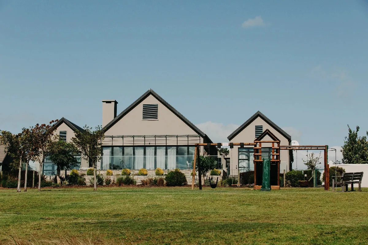 Modern house with large windows and a playground in a grassy yard