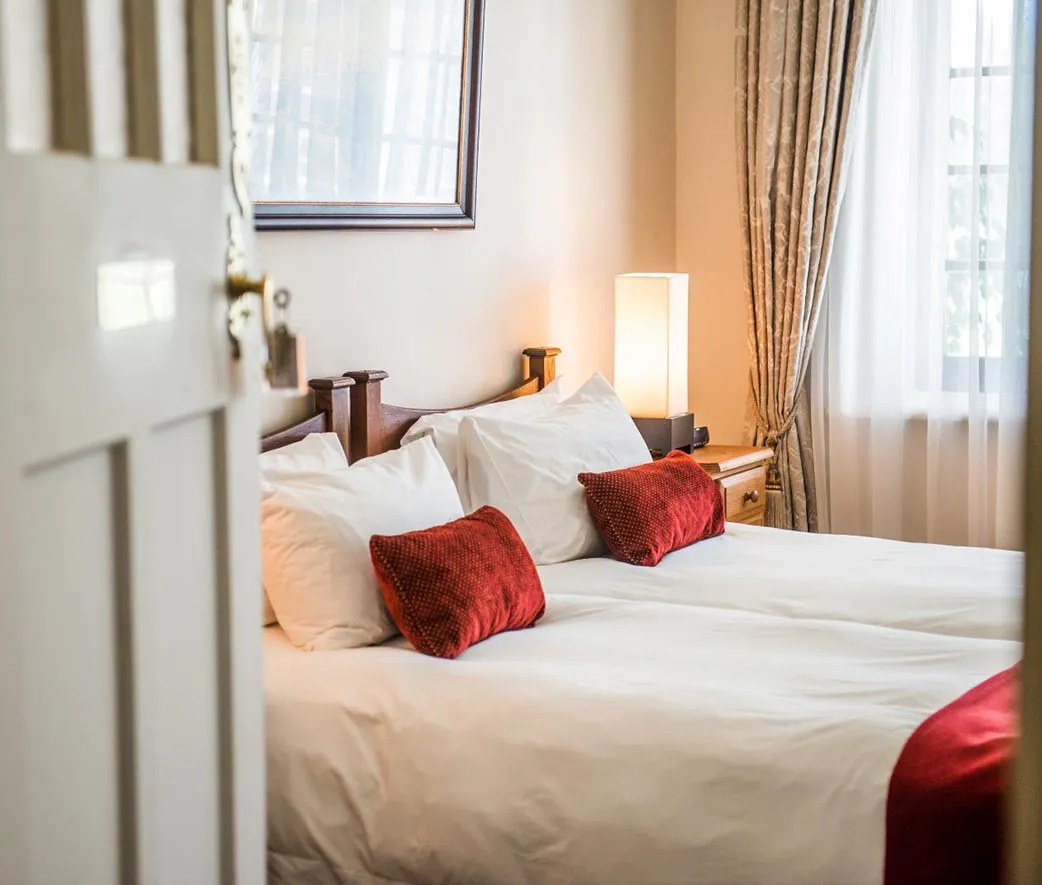 A neatly made bed with red and white pillows in a bedroom
