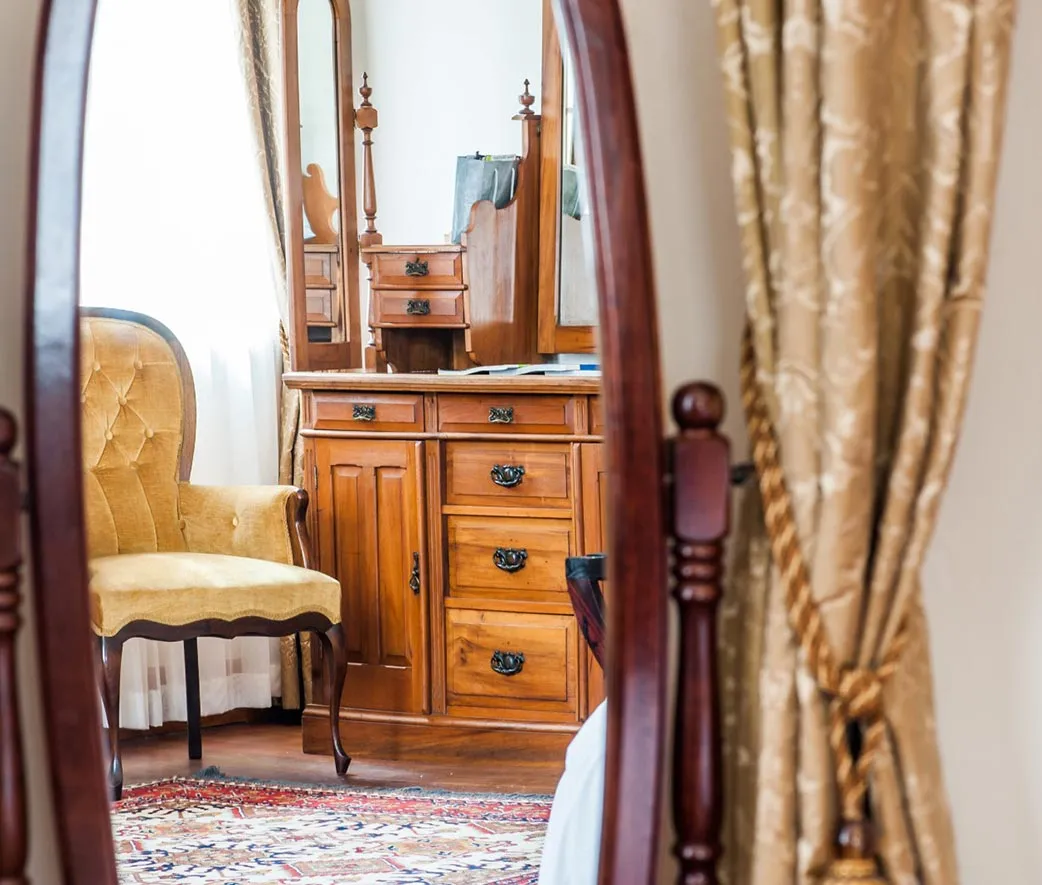 Reflection of antique wooden furniture and yellow chair in a mirror