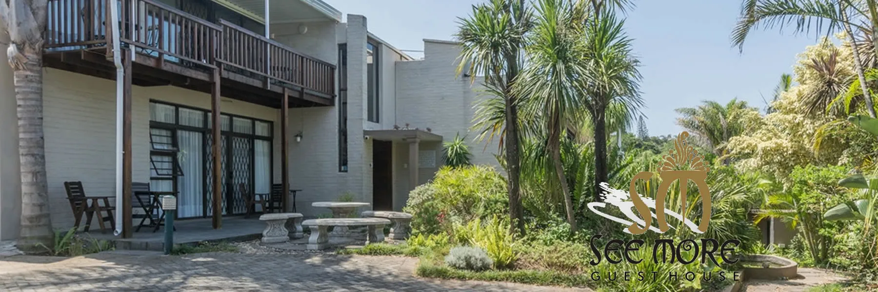 Modern house with balcony surrounded by lush greenery and palm trees