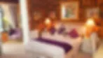 Blurry image of a bedroom with a bed pillows and lamps