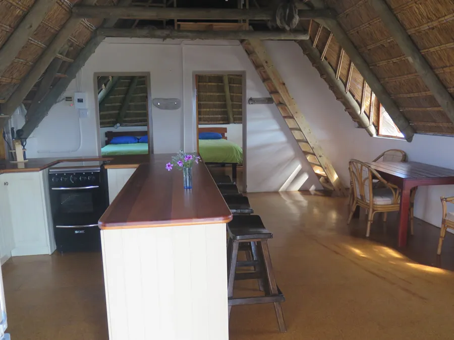 Wooden interior with kitchen dining area and two beds under slanted ceiling