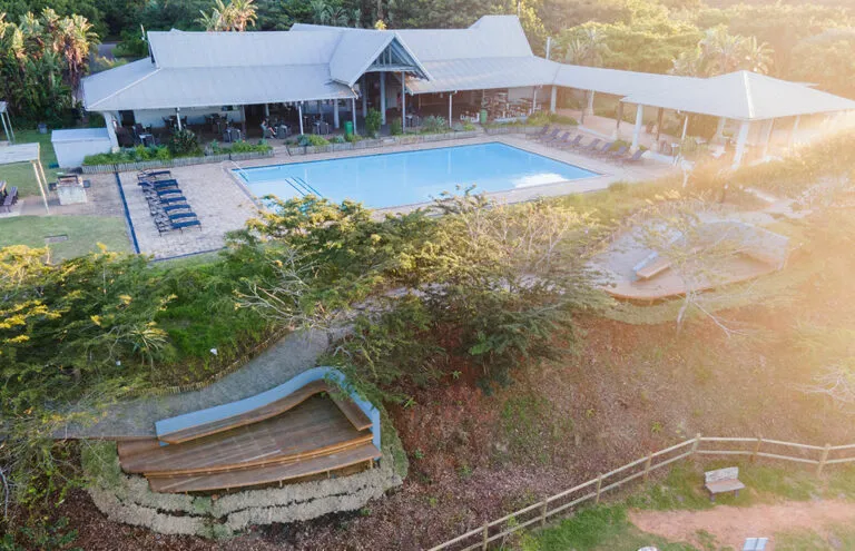 Aerial view of a resort with a pool lounge chairs and greenery