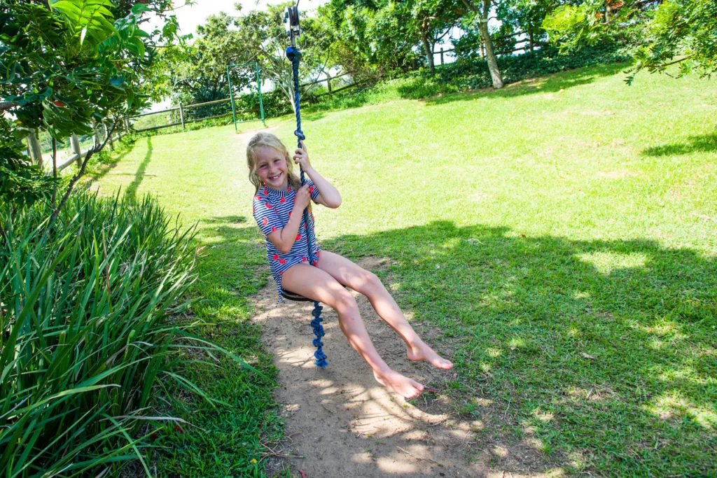 Child swinging on a rope in a grassy park area