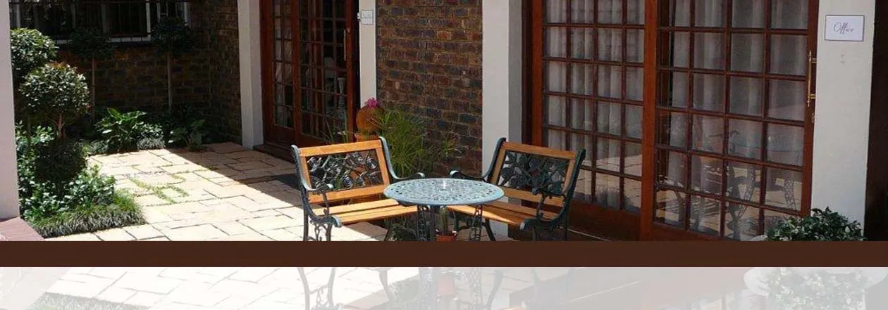 Patio with two chairs and a table outside a brick building with large windows