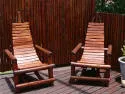 Two wooden chairs on a wooden deck with a wooden fence background