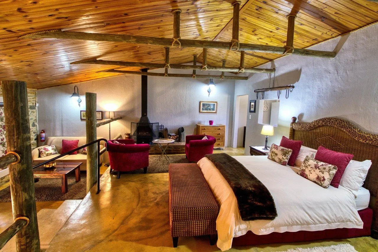 Cozy bedroom with wooden ceiling fireplace and red armchairs in a rustic setting