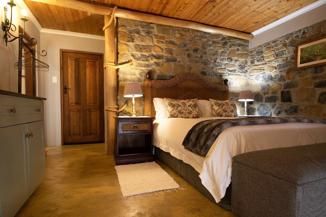Cozy bedroom with wooden ceiling stone wall and large bed with pillows