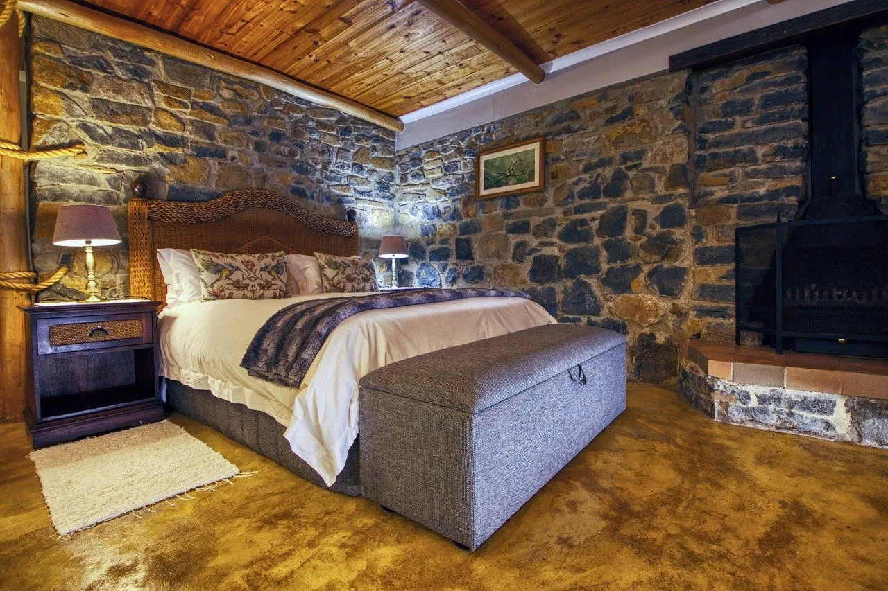 Cozy bedroom with stone walls wooden ceiling and a fireplace