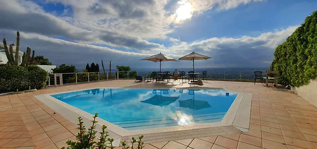Swimming pool with lounge chairs and umbrellas overlooking a scenic view