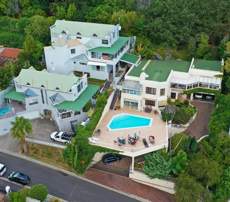 Aerial view of a large house with a pool and surrounding greenery