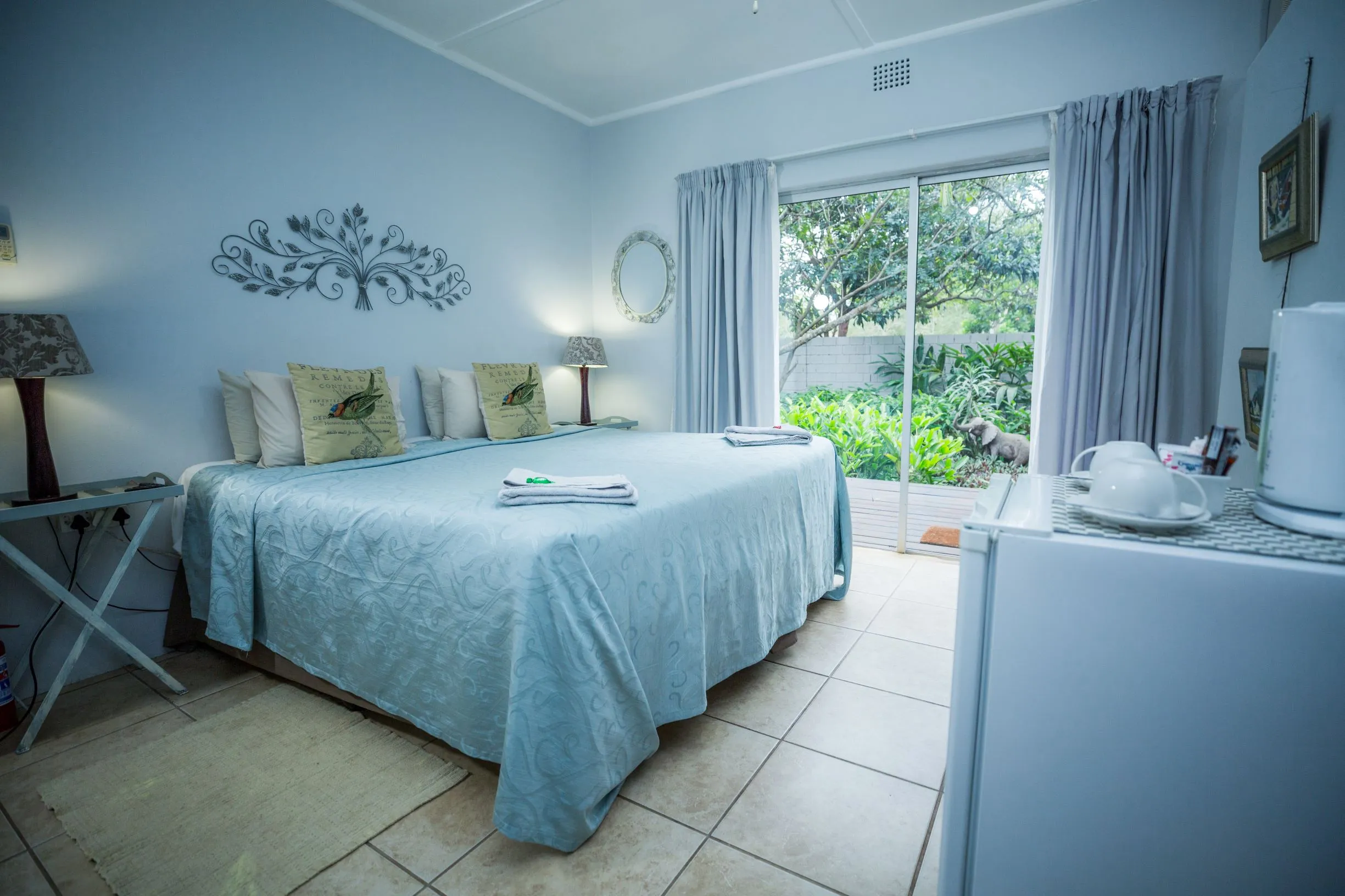 Cozy bedroom with a large bed sliding glass door and a small fridge