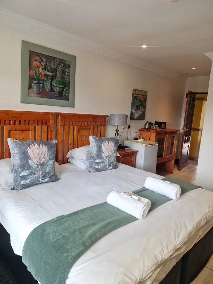 Bedroom with a large bed wooden headboard and floral artwork on the wall