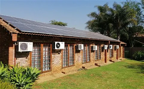 Brick building with solar panels on roof and air conditioners on exterior wall