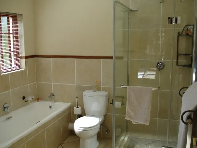 Beige bathroom with white toilet bathtub and glass shower enclosure
