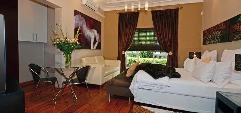 Modern bedroom with large bed sofa and dining table with flowers