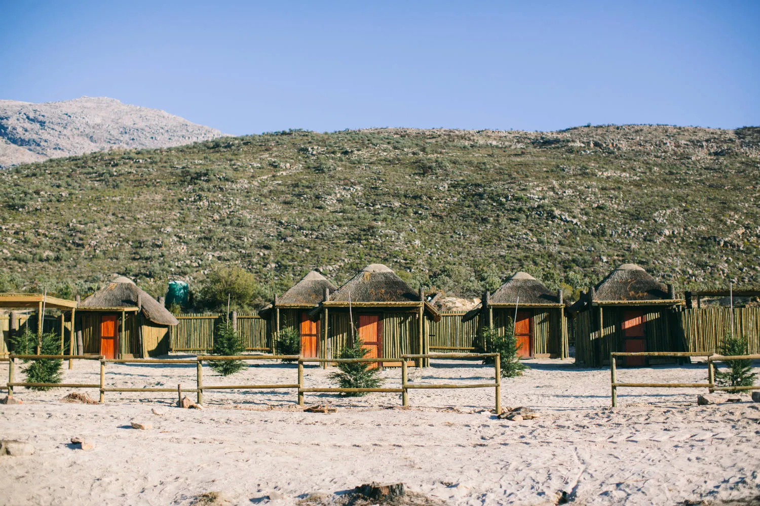 Row of traditional huts with red doors in a mountainous desert landscape