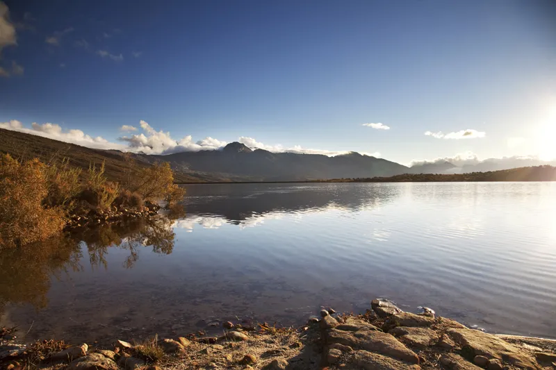Calm lake with mountains in the background under a clear blue sky