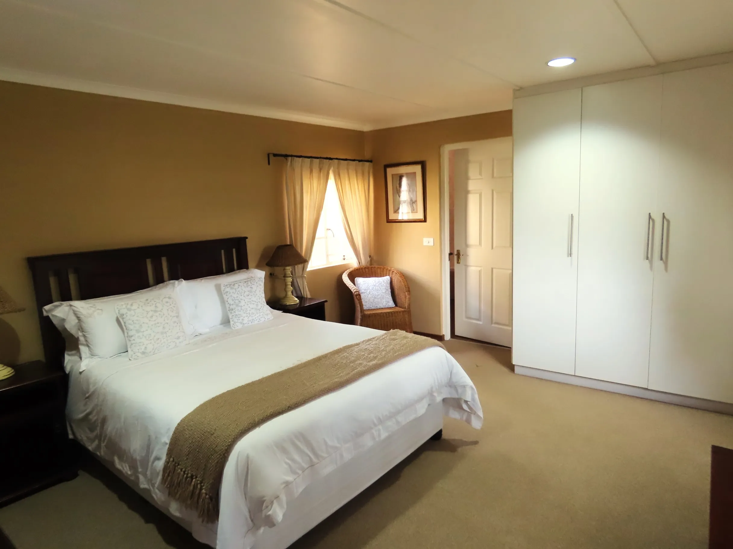 Bedroom with a neatly made bed armchair and wardrobe