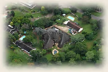 Aerial view of a large house with a pool and surrounding greenery