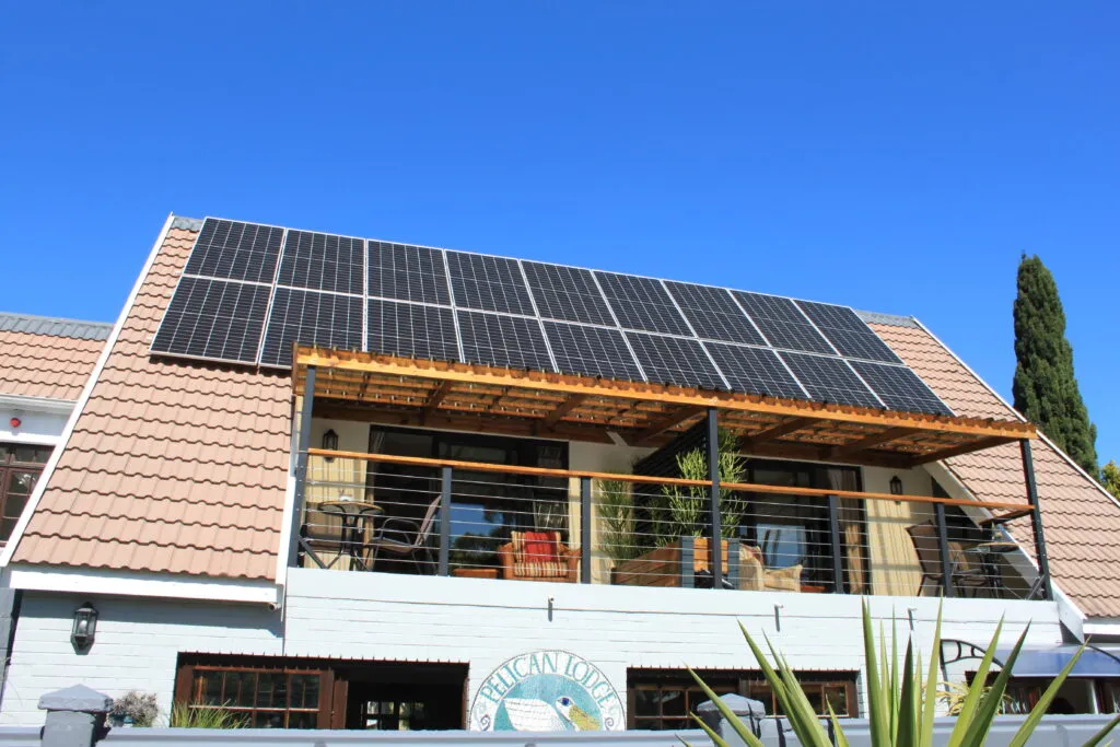 Solar panels on a buildings roof with a balcony and plants