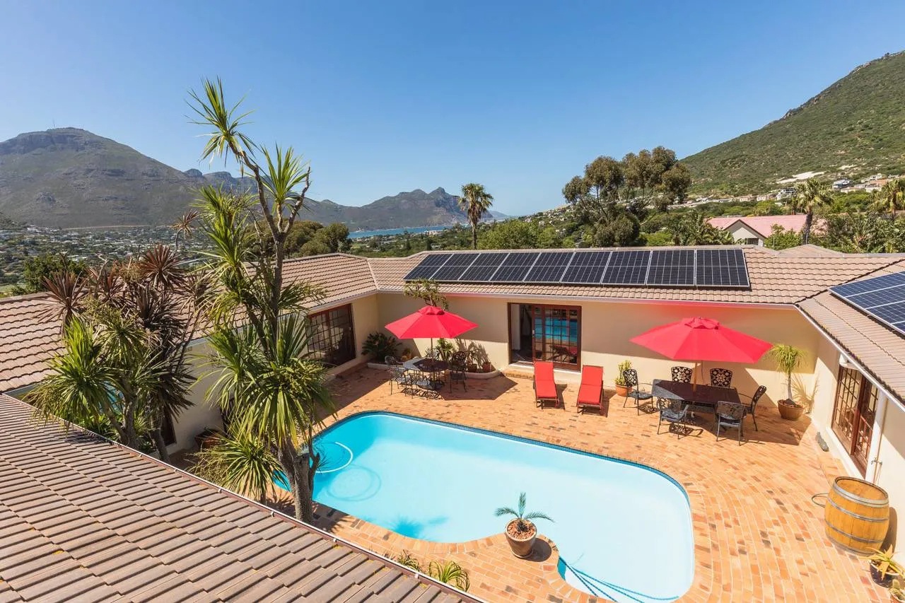 House with pool solar panels and mountain view under clear sky