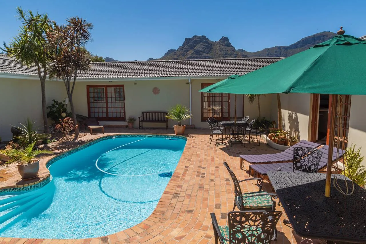 Swimming pool with lounge chairs and umbrellas in a sunny backyard setting