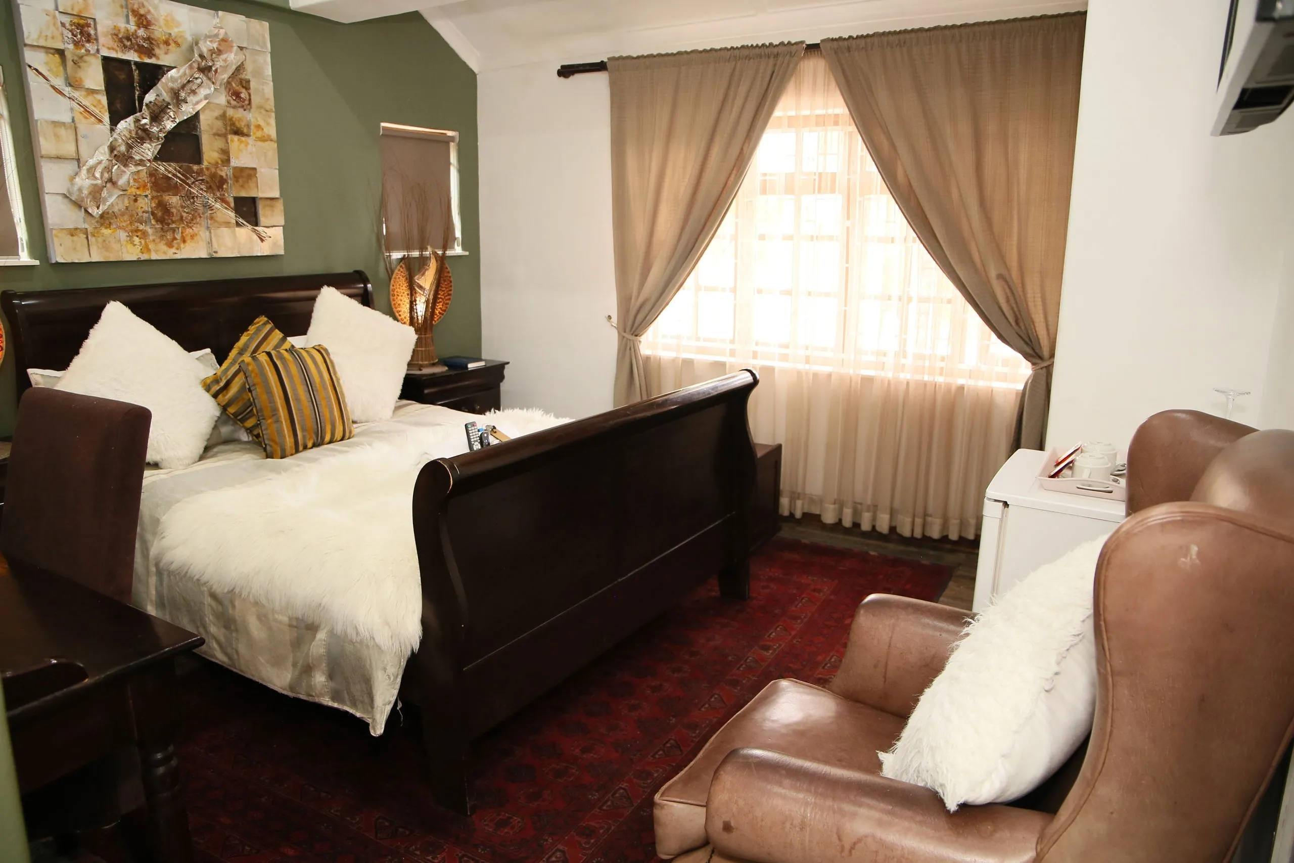 Cozy bedroom with a large bed armchair and window with curtains