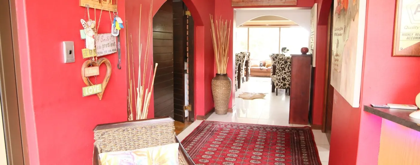 Red hallway with decor leading to a living room with furniture