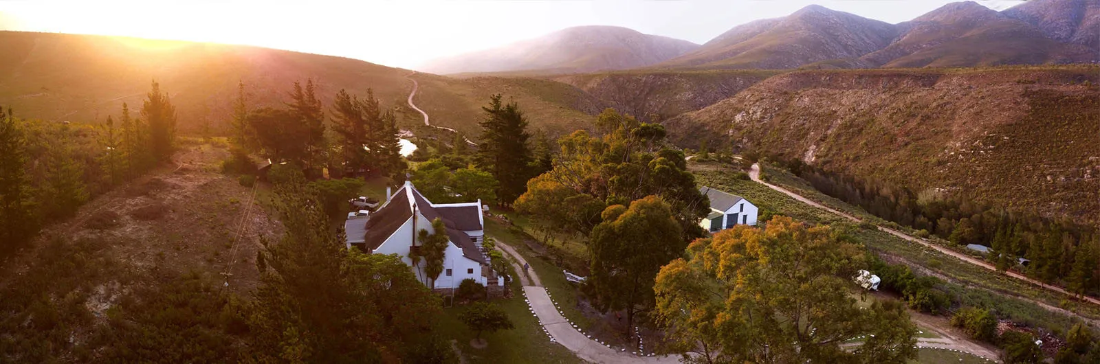 Sunset over a valley with houses trees and mountains in the background