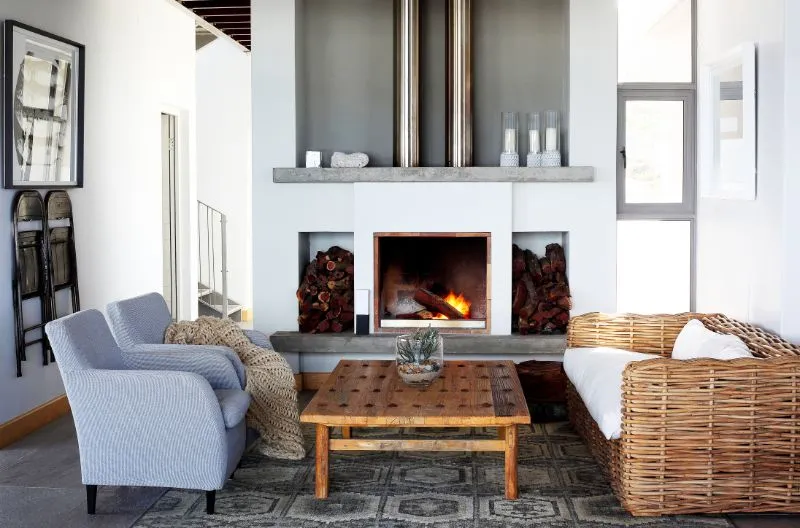 Cozy living room with fireplace wicker sofa armchairs and wooden coffee table