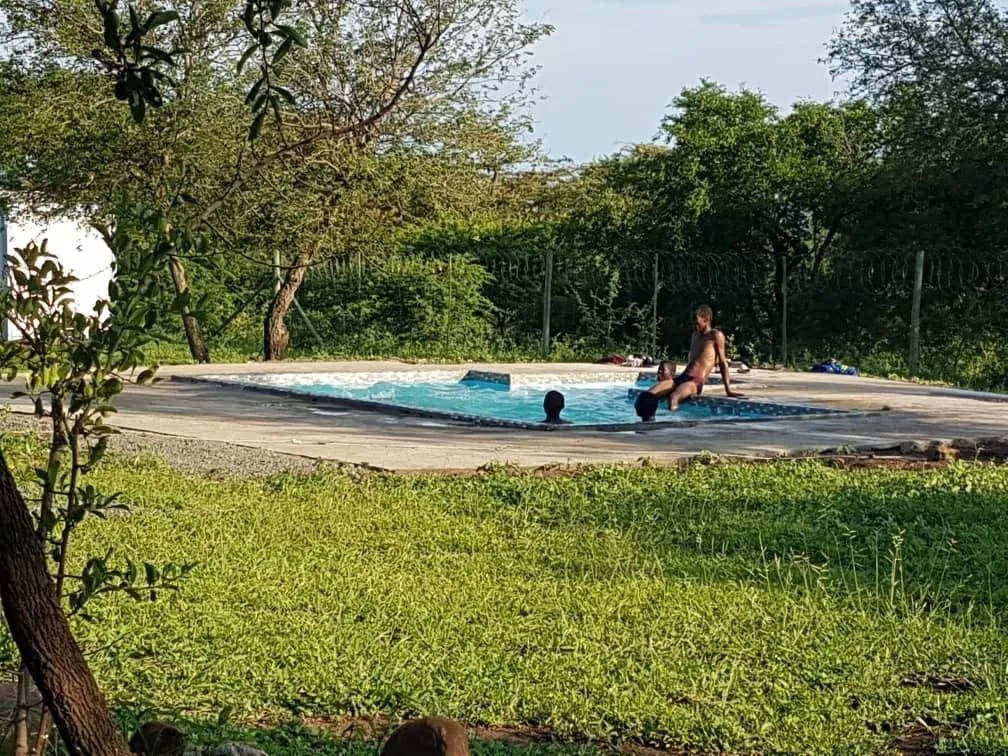 Person sitting in a small pool surrounded by greenery and trees