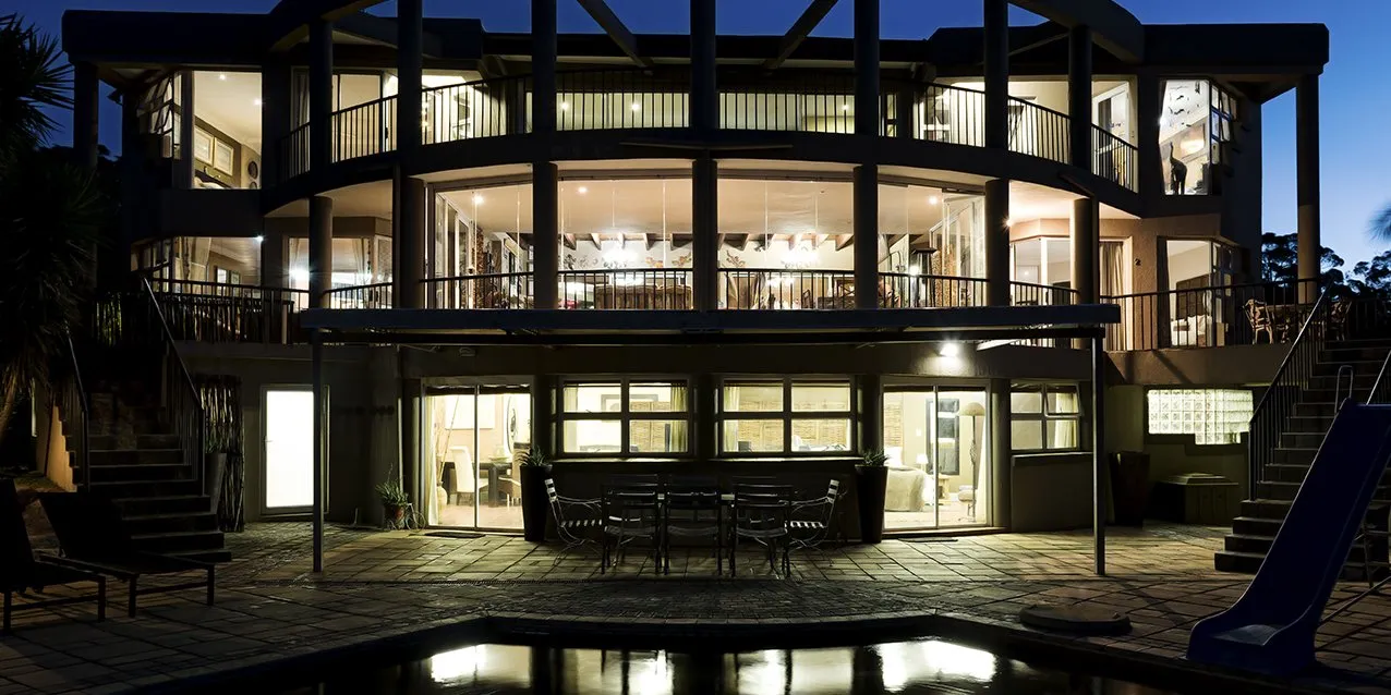 Modern house at night with large windows and outdoor seating area