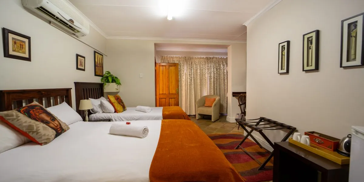 Hotel room with two beds orange blankets and wall art