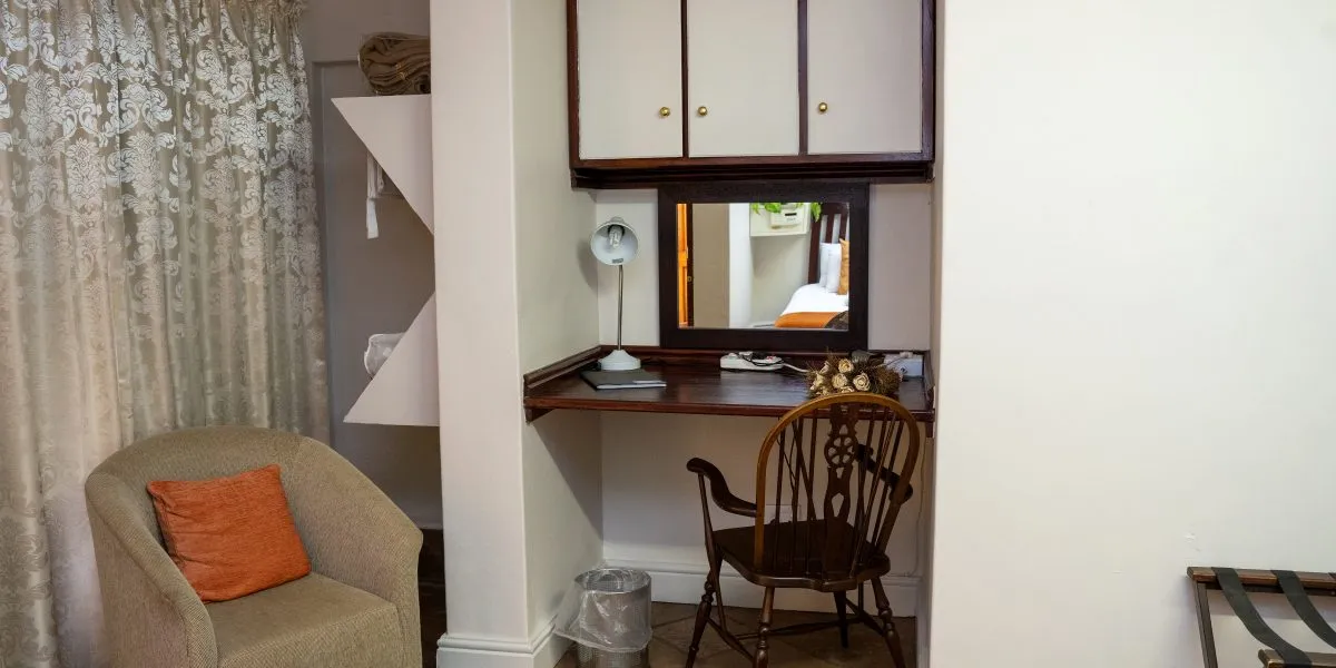 Wooden desk with chair lamp and mirror in a cozy room with armchair