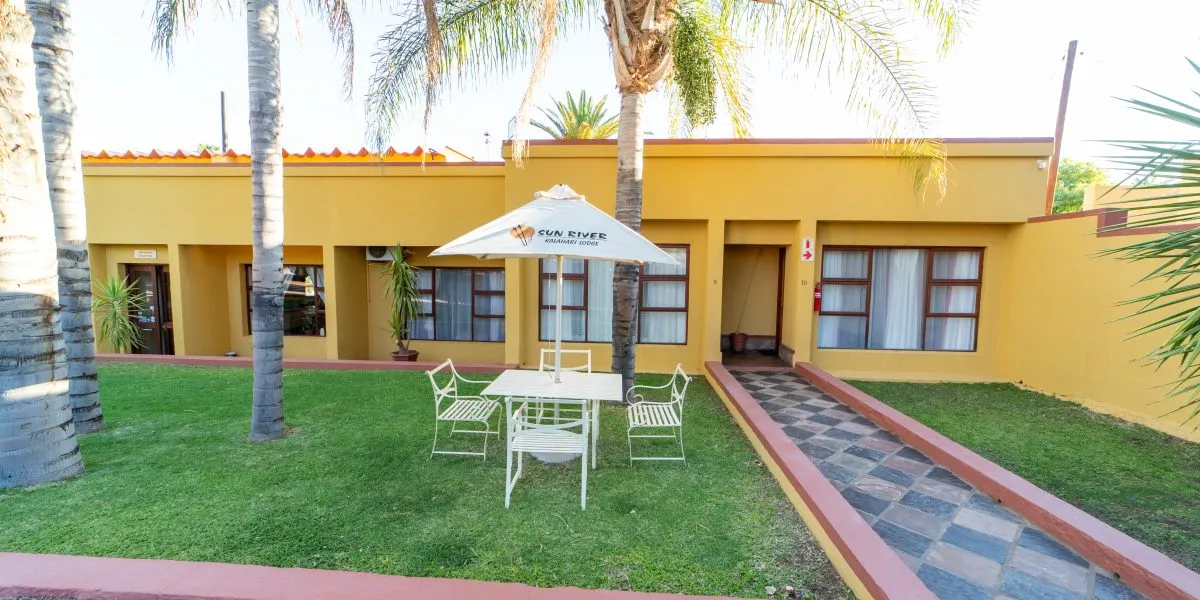 Yellow building with outdoor seating area palm trees and green lawn