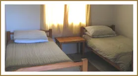 Two single beds in a small bright bedroom with wooden furniture