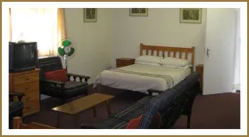 Cozy bedroom with bed sofa dresser and fan framed pictures on walls