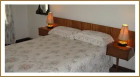A neatly made bed with floral bedding in a bedroom with wooden headboard