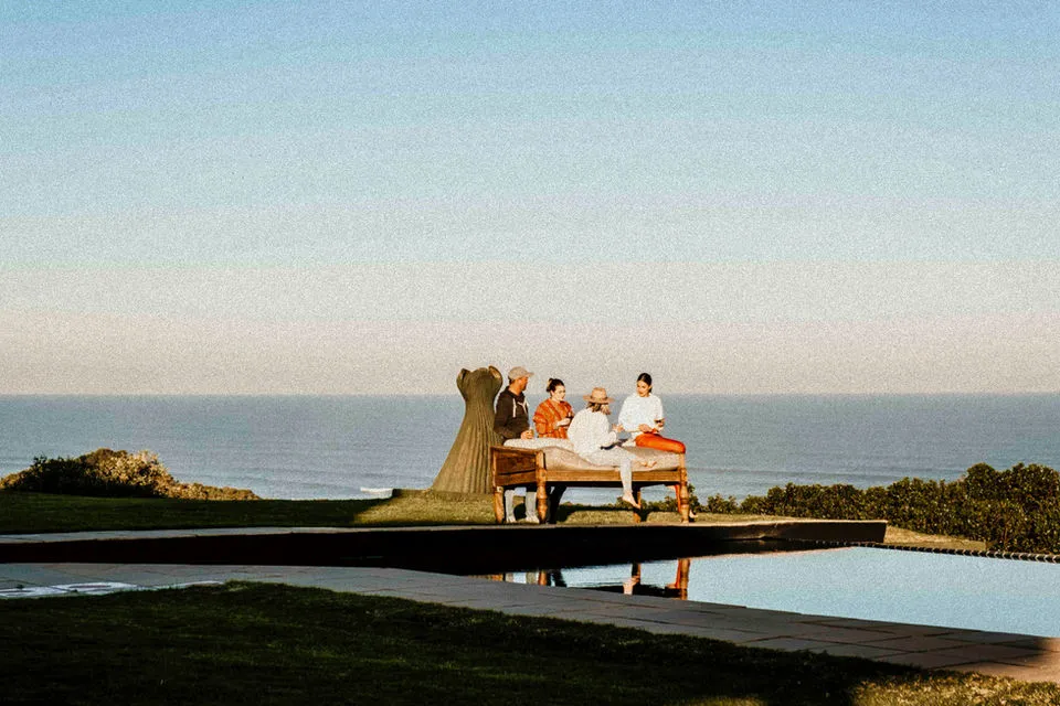 Four people at a table overlooking the ocean with a sculpture nearby