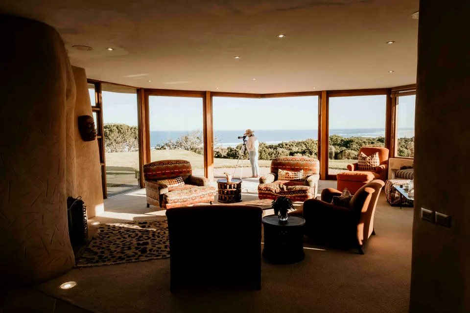 Living room with large windows overlooking the ocean person standing outside