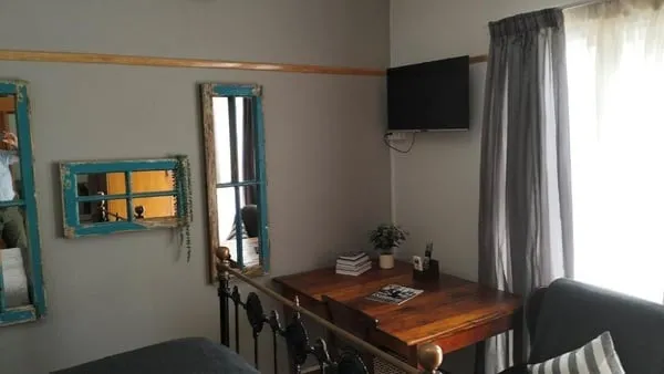Cozy room with a wooden table TV mirrors and a window with curtains