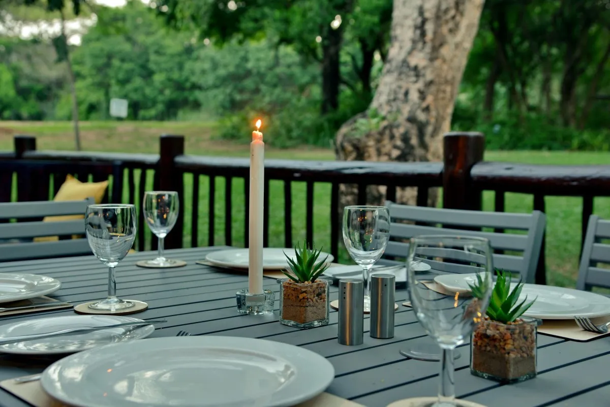 Outdoor dining table set with wine glasses plates and a lit candle