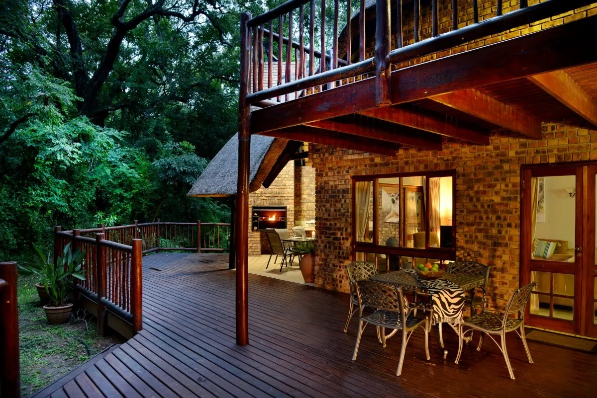 Wooden deck with table and chairs overlooking a lush garden at night