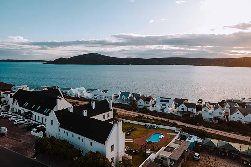 Coastal town with white houses blue sea and a swimming pool at sunset