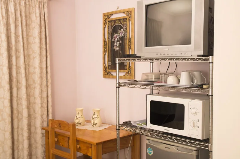 Small room with a TV microwave and a wooden table with vases